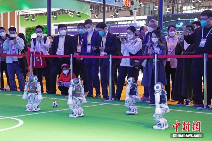第五届中国国际进口博览会在国家会展中心(上海)举办。技术装备展区的人工智能体验区，参观者观看机器人踢足 ...