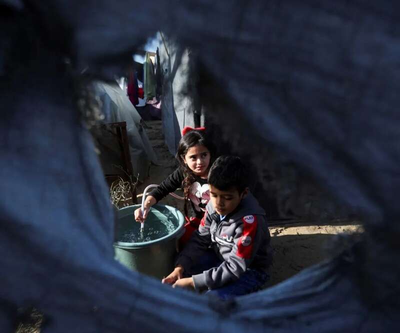 流离失所的巴勒斯坦儿童在汗尤尼斯一处临时避难所内打水