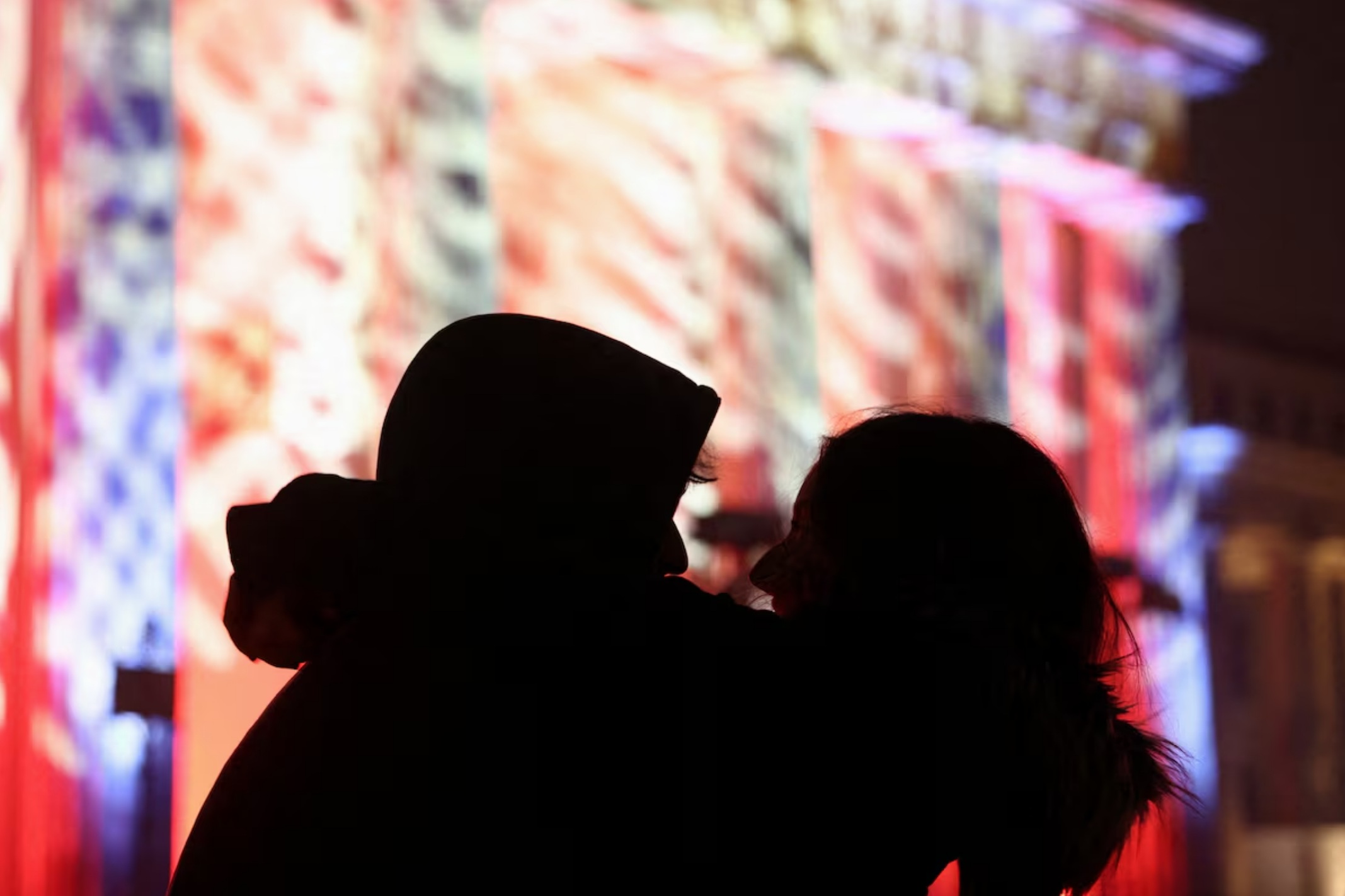 在德国柏林，两人在新年庆祝活动中拥抱，背景是勃兰登堡门